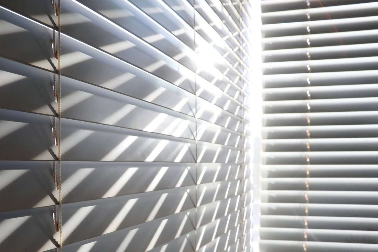 Modern Venetian blinds with sunlight streaming through at an angle at Desert Shades and Drapery near Phoenix, AZ